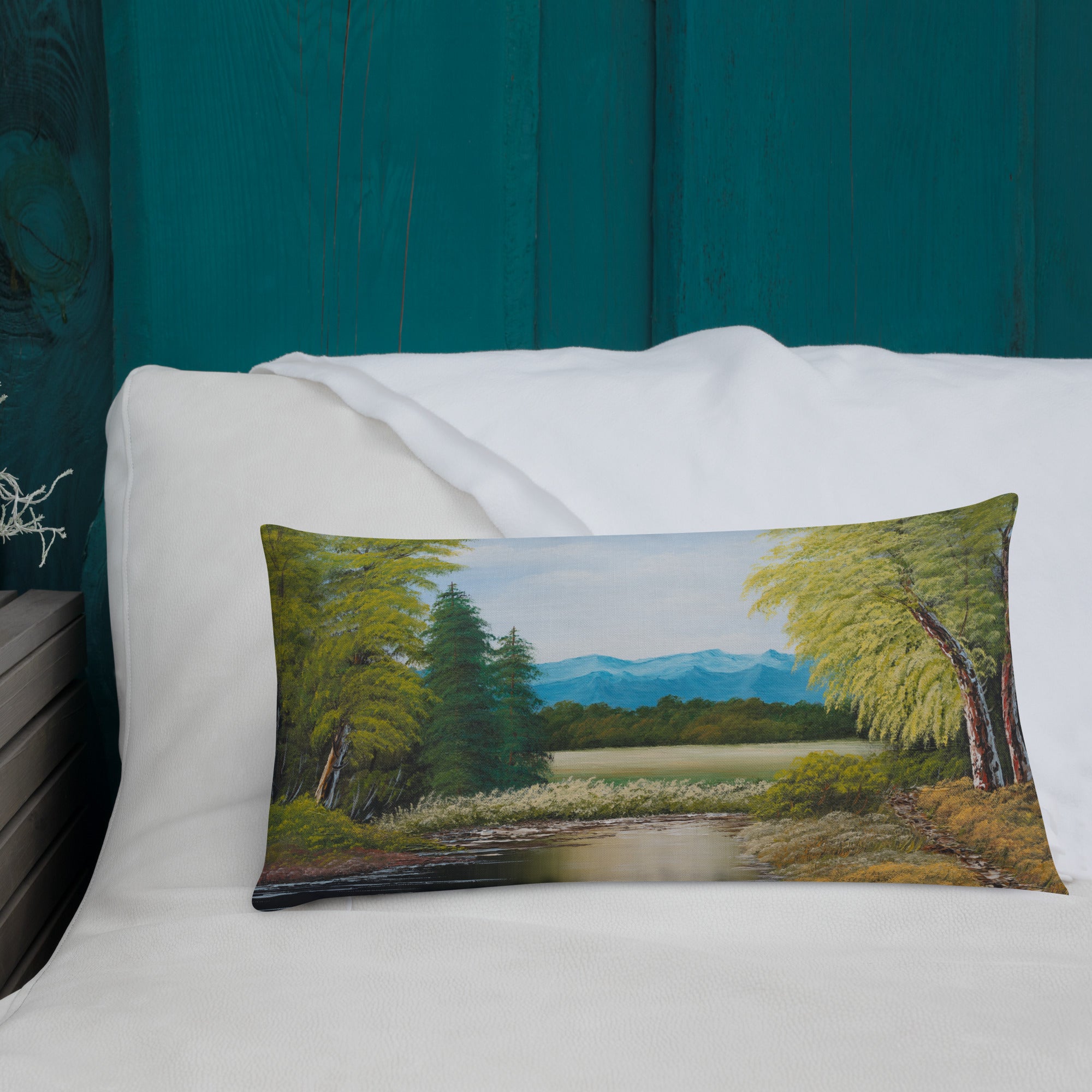 Exclusive and decorative premium designer cushion with an all-over print of a painted landscape with a large glade and a big green tree under a blue sky.