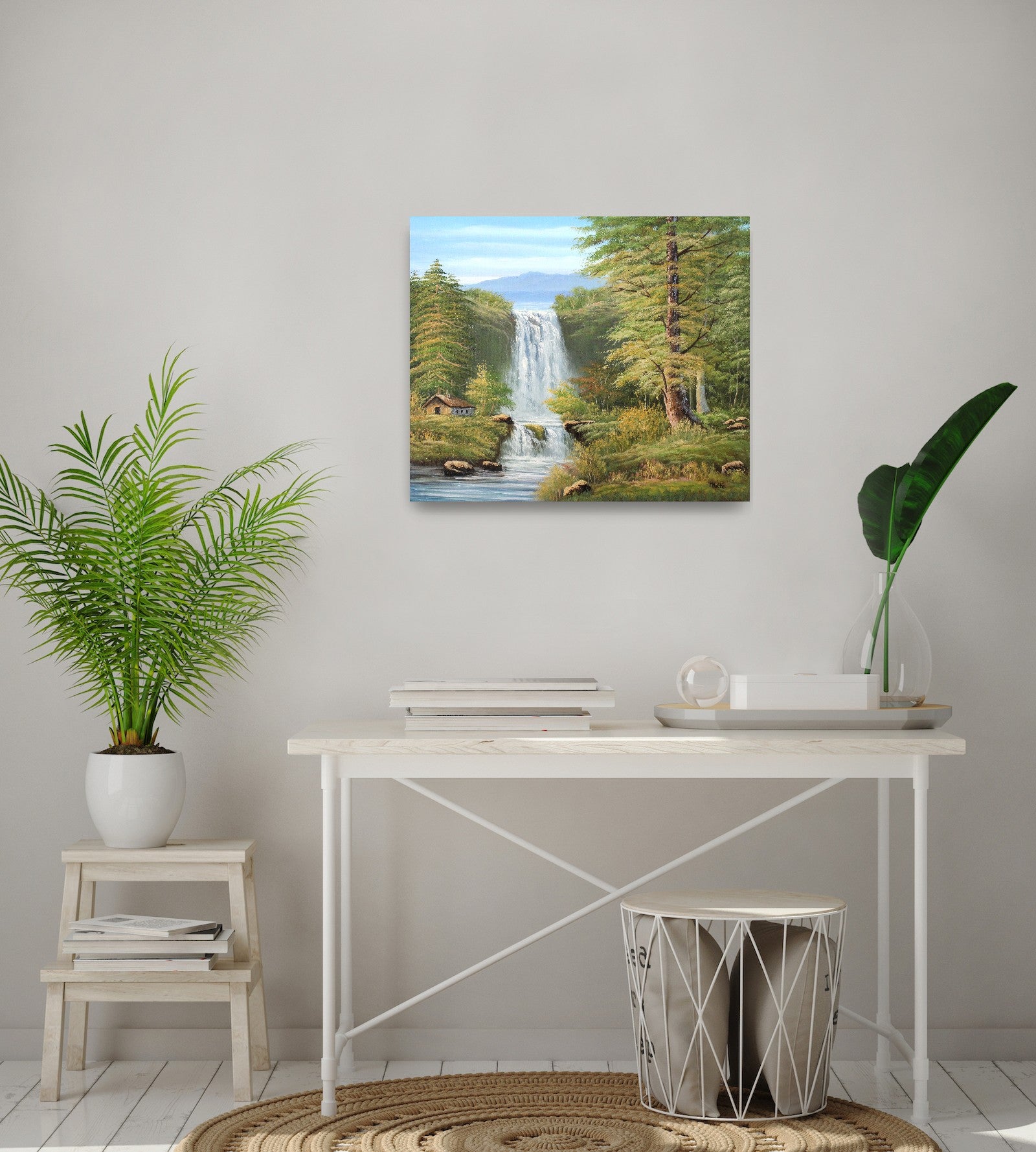 Original artwork by Tobias Nolte titled “Twin Falls”. A hand-painted oil painting (60x50 cm) featuring two cascading waterfalls in a lush forest scene with mountains, tall green trees, and a small wooden cabin by the riverbank, displayed in a bright interior with white furniture and plants.
