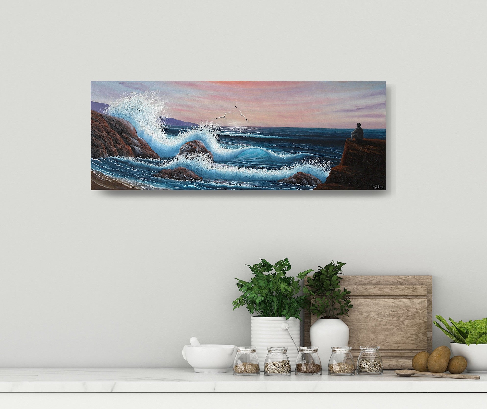 Oil painting on canvas showing a dramatic seascape with large blue waves crashing against rocky cliffs at sunset. Pink and purple clouds fill the sky. A grey person sits on a rock, gazing out at the ocean. The painting is displayed on a white wall.