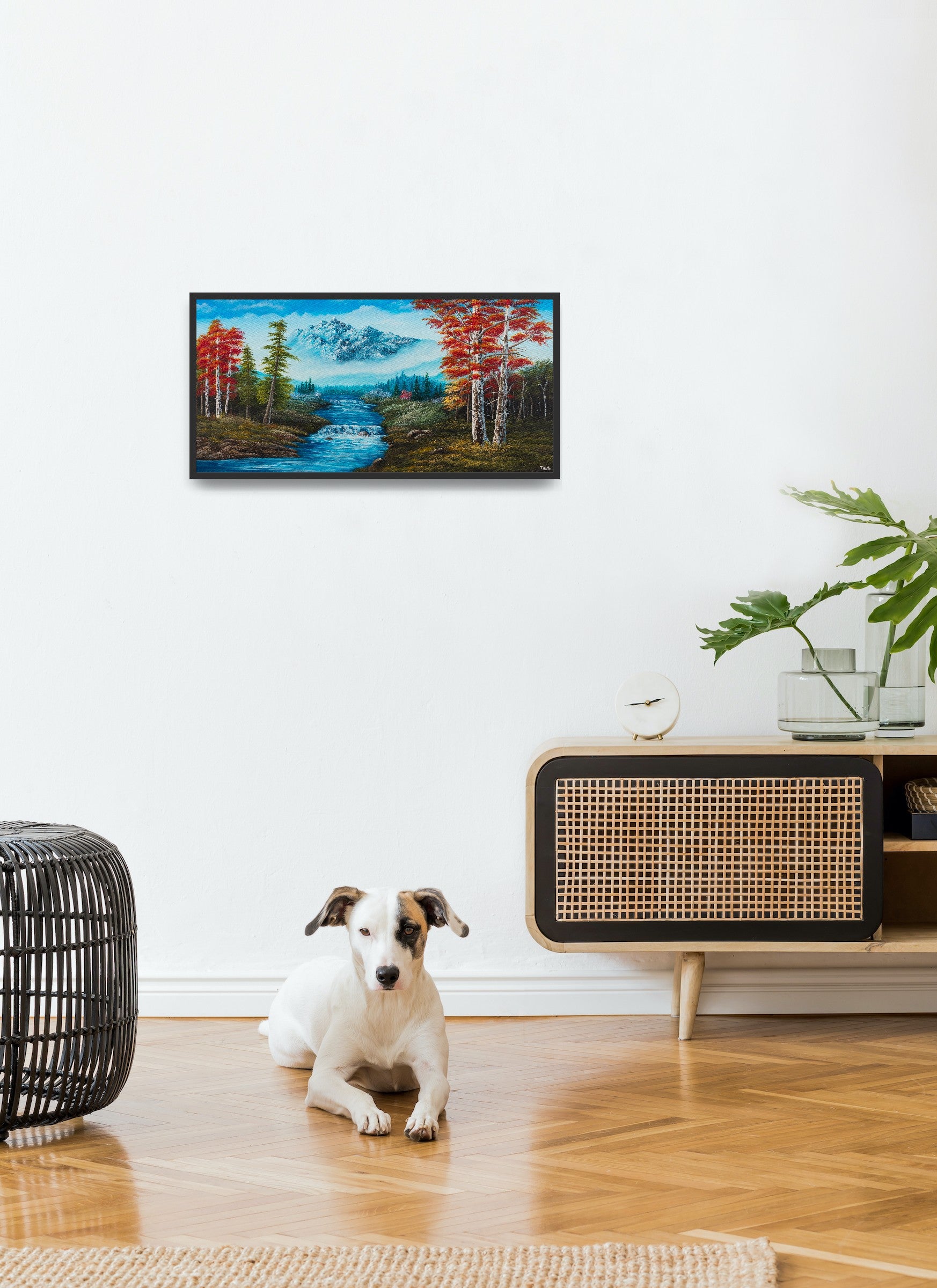 Original artwork by Tobias Nolte titled “Forest Fantasy”. A hand-painted acrylic painting (80x40 cm) featuring a romantic landscape with red leaf trees, many fir trees, a big bluish mountain, and a waterfall, displayed in a modern living room.