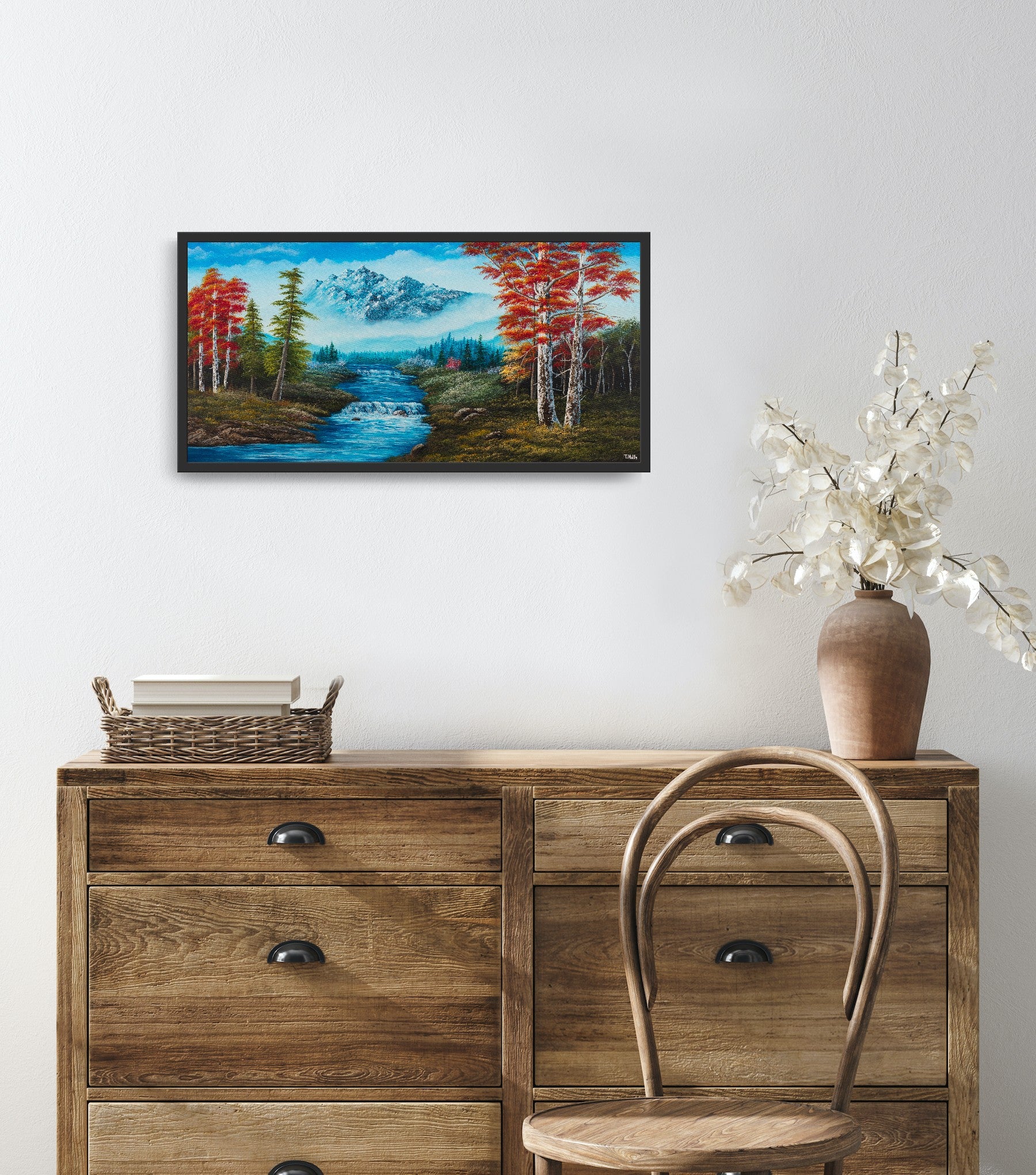 Original artwork by Tobias Nolte titled “Forest Fantasy”. A hand-painted acrylic painting (80x40 cm) featuring a romantic landscape with red leaf trees, many fir trees, a big bluish mountain, and a waterfall, displayed in a modern interior setting.