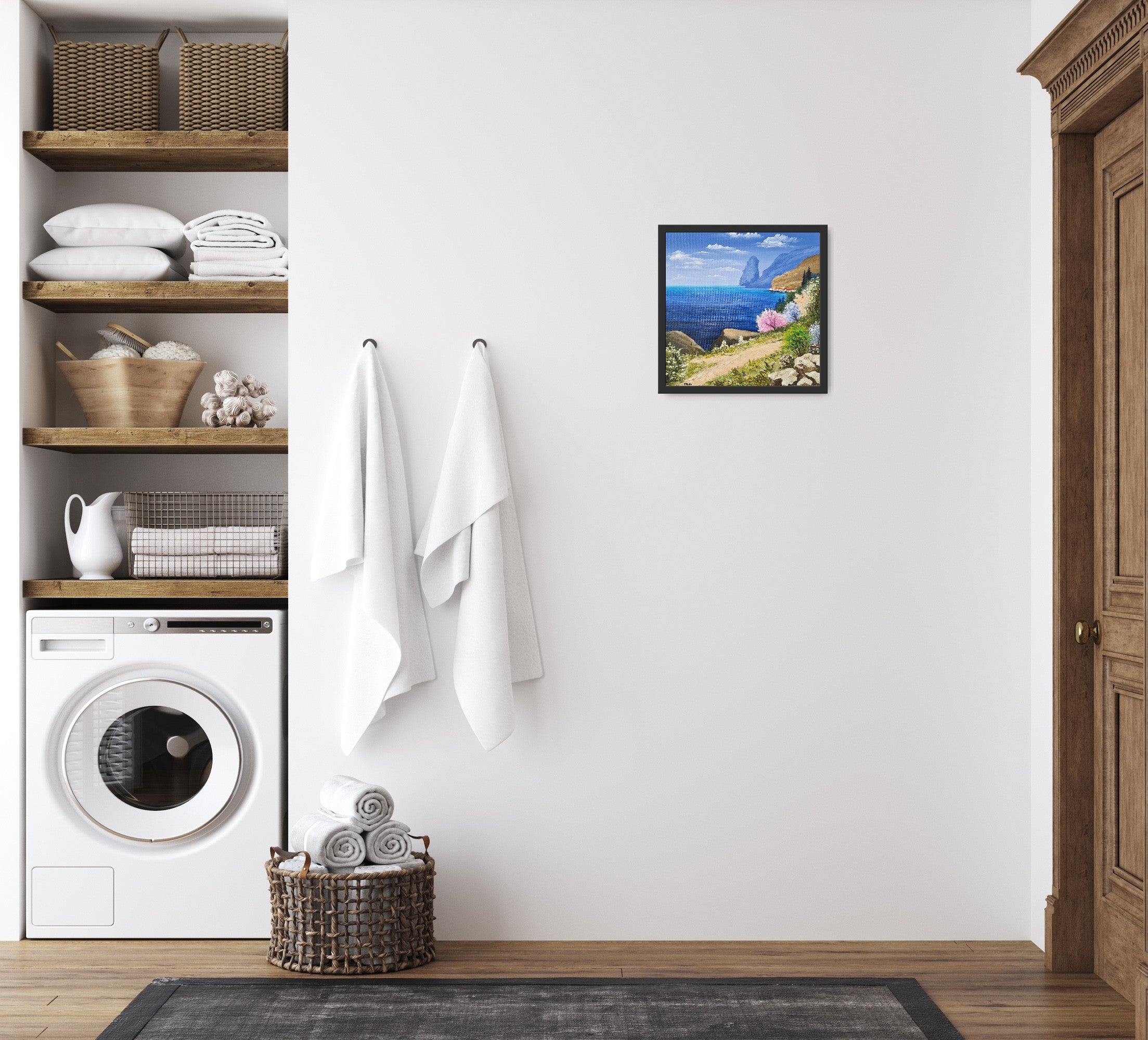Original artwork by Tobias Nolte titled “Sea View”. A framed, hand-painted oil painting (30x30 cm) featuring a blue sea panorama along a hiking trail, next to colorful trees and rocks, displayed in a bathroom.
