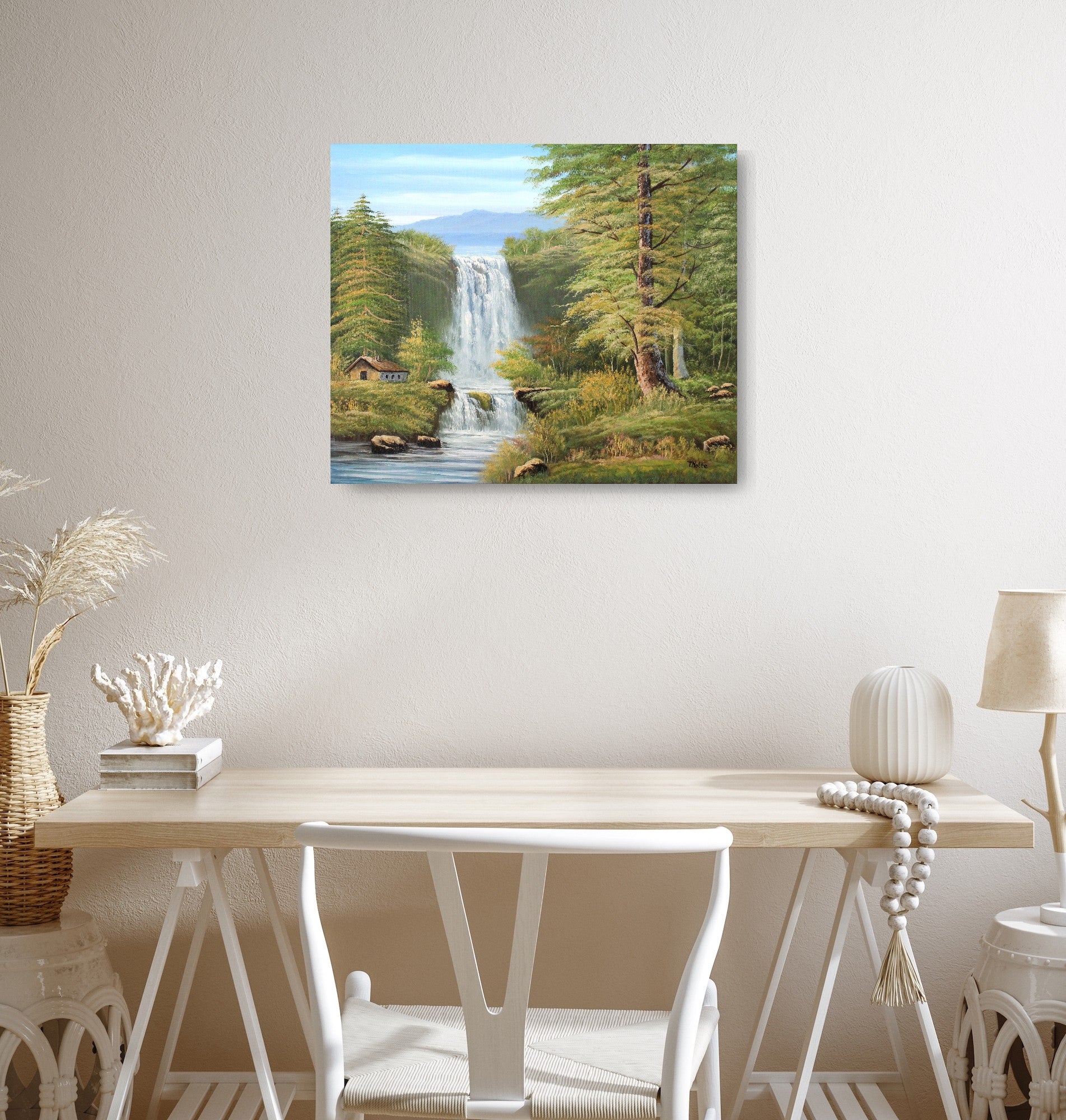 Original artwork by Tobias Nolte titled “Twin Falls”. A hand-painted oil painting (60x50 cm) featuring two cascading waterfalls in a lush forest scene with mountains, tall green trees, and a small wooden cabin by the riverbank, displayed in a bright interior with natural wooden furniture.